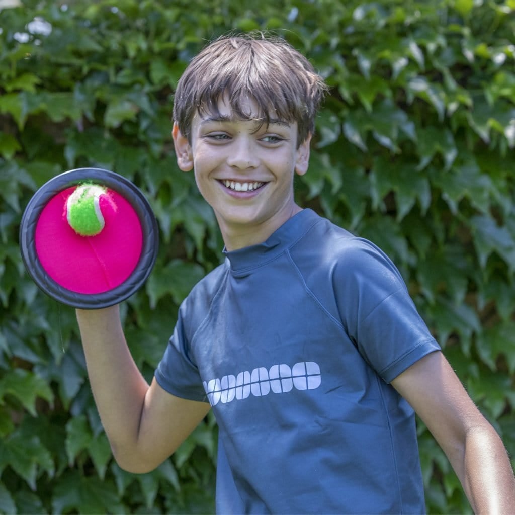Child in backyard catching a ball with The Original Grip Ball